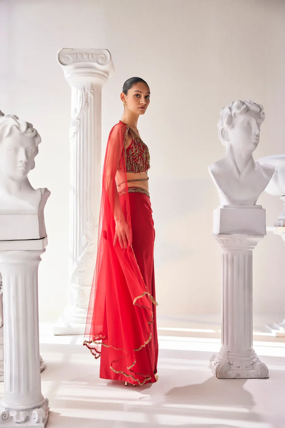 Elegant Red Ensemble Features A Royal Satin Skirt, Fully Embroidered Blouse, Belt And A Cape In A Soft Net.